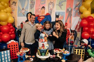 Colorful birthday party scene with balloons, decorations, and people gathered around tables celebrating.