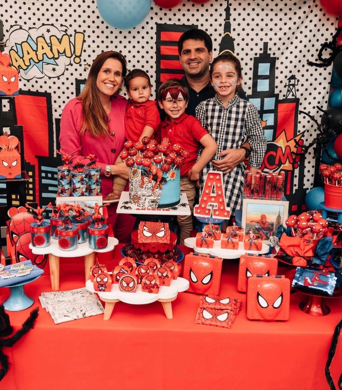 A Spider-Man themed birthday party setup with red decorations and dessert tables featuring superhero motifs and treats.