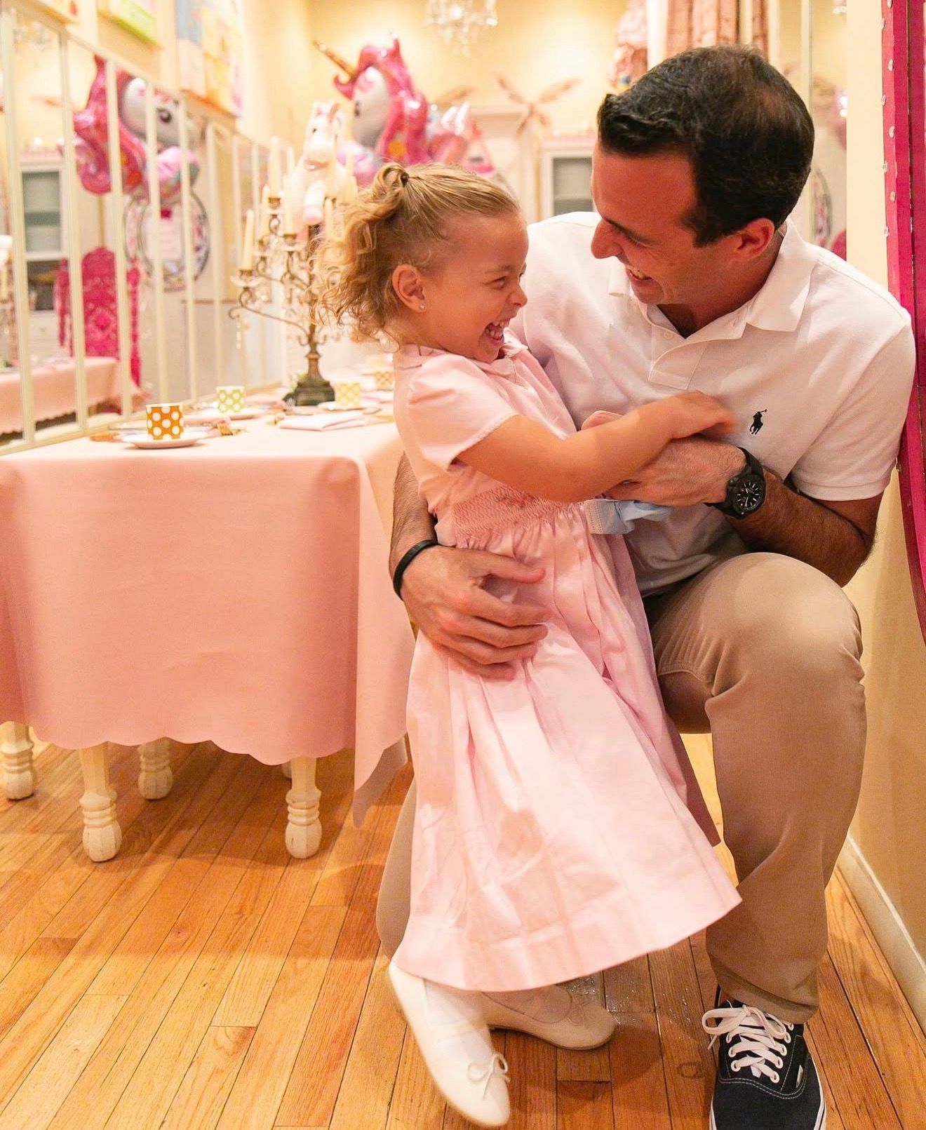 A tender moment shared between an adult and child in pink dress during a special celebration in a decorated room.