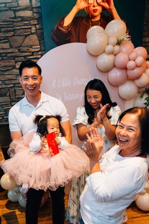A joyful family celebration with pink balloons and tulle decorations at a birthday party.