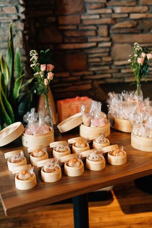 Bamboo steamer baskets filled with dim sum dumplings arranged in a row on a wooden table with warm lighting.