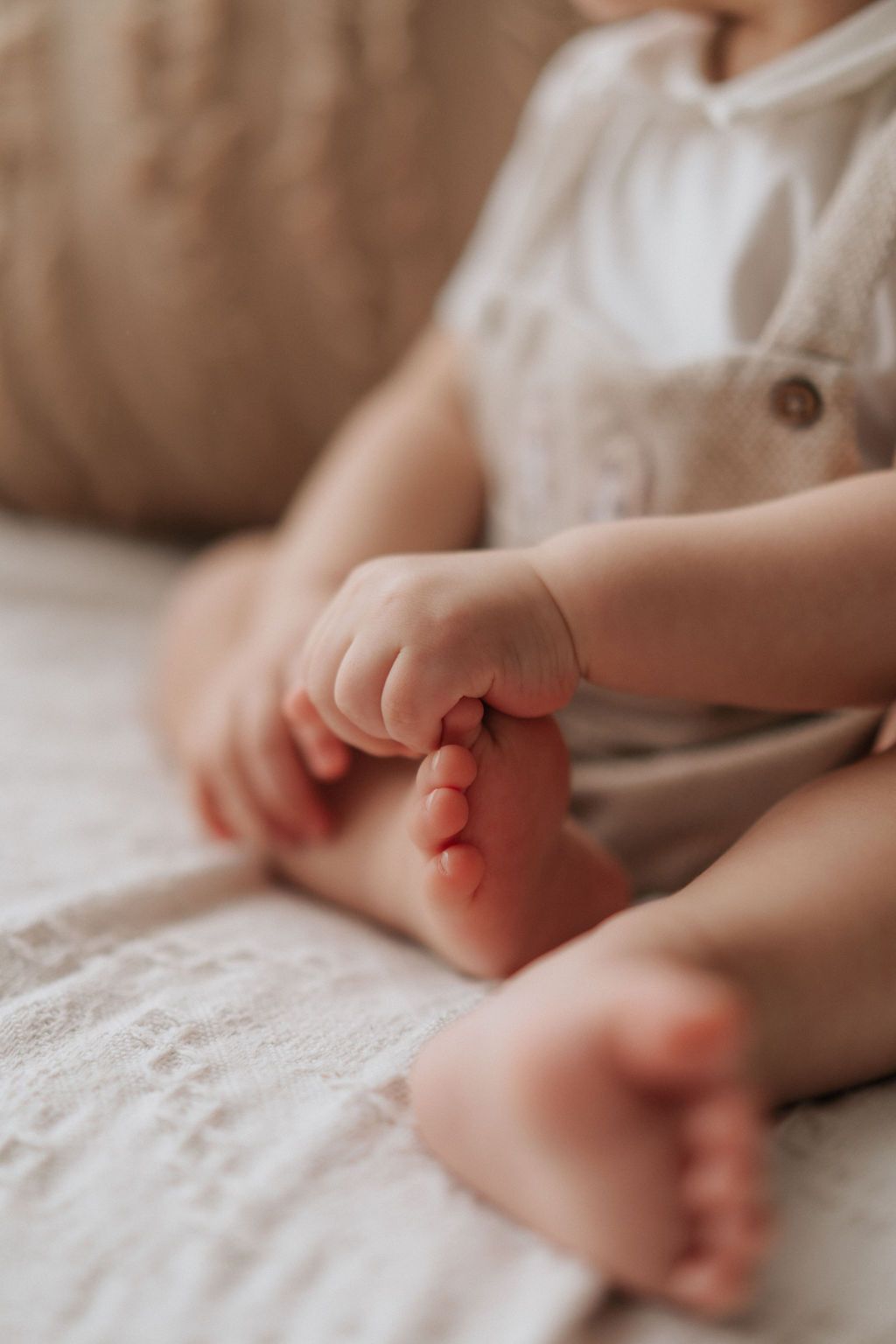 Close-up series of tiny baby feet resting on soft white textured fabric in natural lighting.在自然光線下，一組特寫鏡頭拍攝了嬰兒嬌嫩的小腳丫，它們靜靜地躺在柔軟的白色紋理布料上。