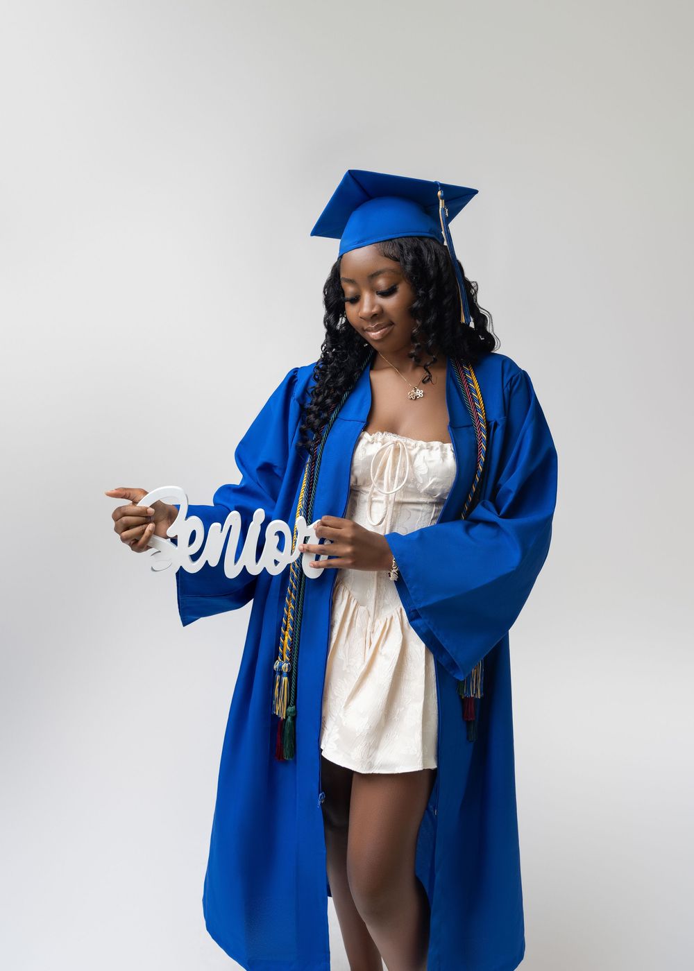 Graduate in royal blue cap and gown poses confidently in a series of celebratory graduation photos.