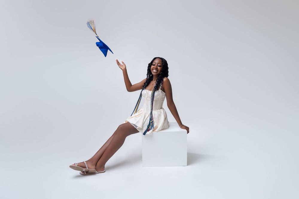 Dancer in white leotard performs elegant contemporary dance movements against light gray background.