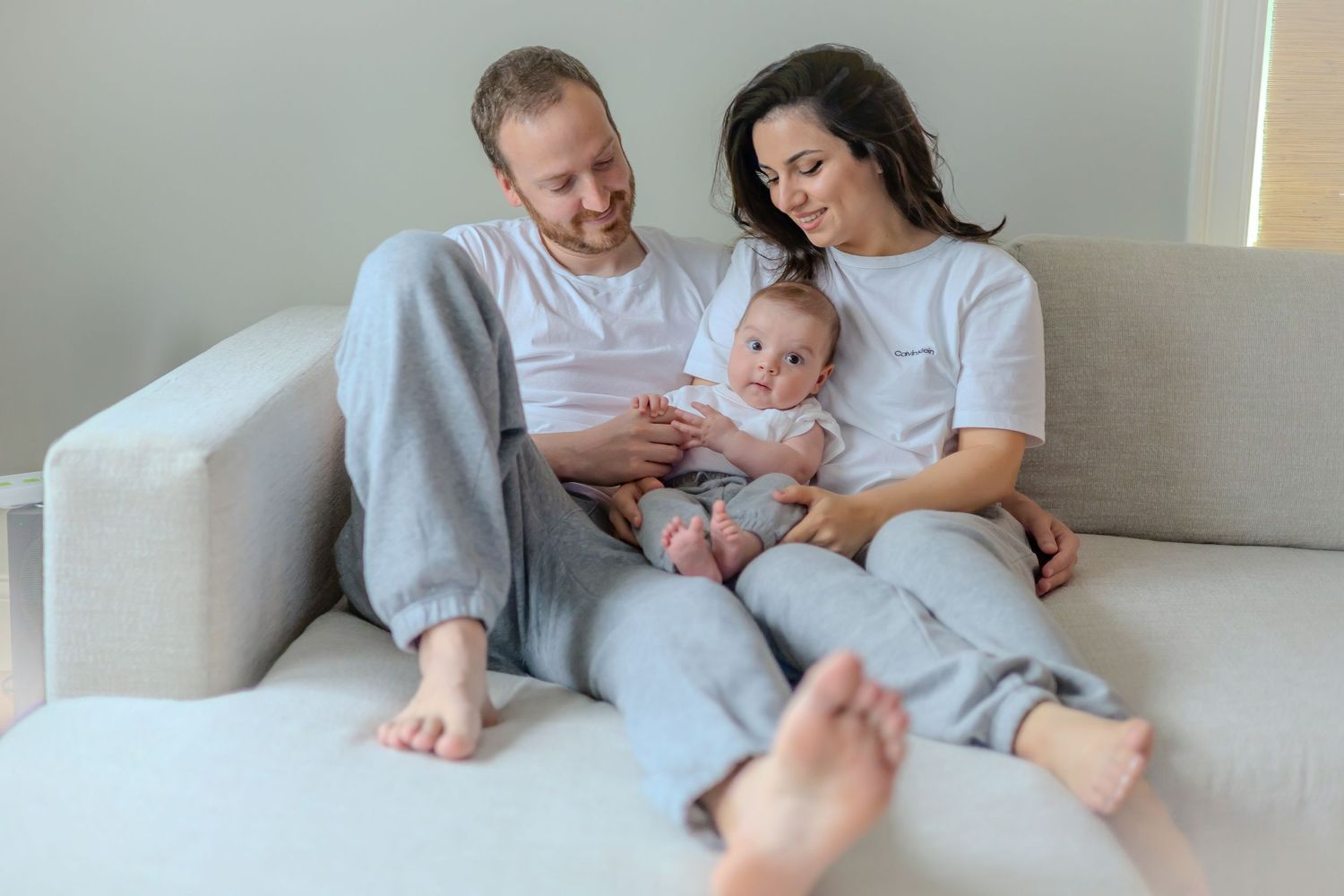 A happy family lounges together on a comfortable white sofa as they share a tender moment at home.