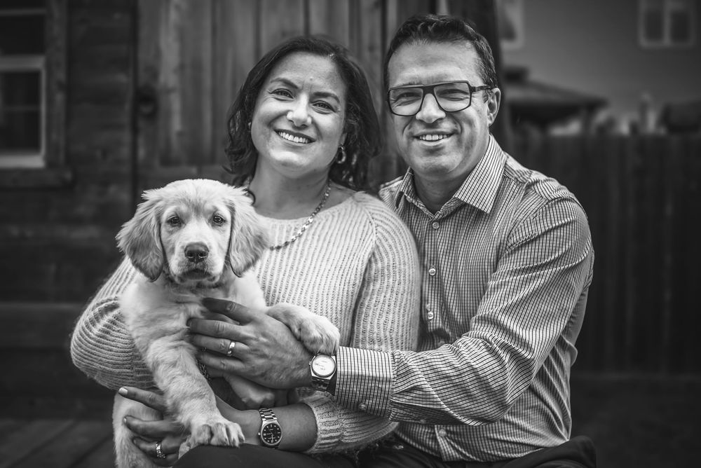 A lovely man and woman couple sit on the deck of the playhouse they build as they hold their new puppy.