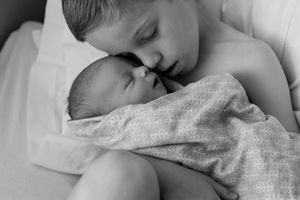 Black and white portrait of sleeping infant on textured blanket.