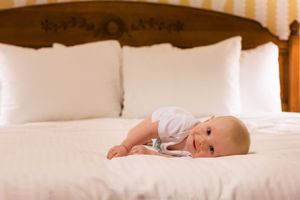 Newborn sleeping peacefully on white bedding in natural window light.