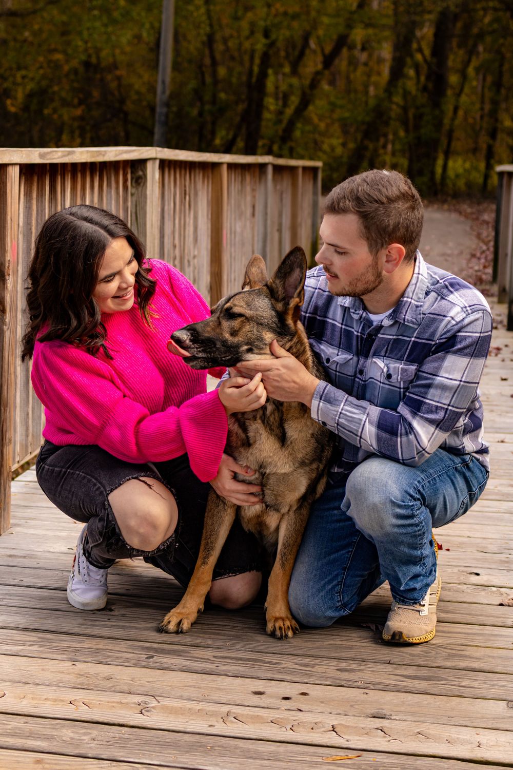 a man and women petting a dog while on a bridge