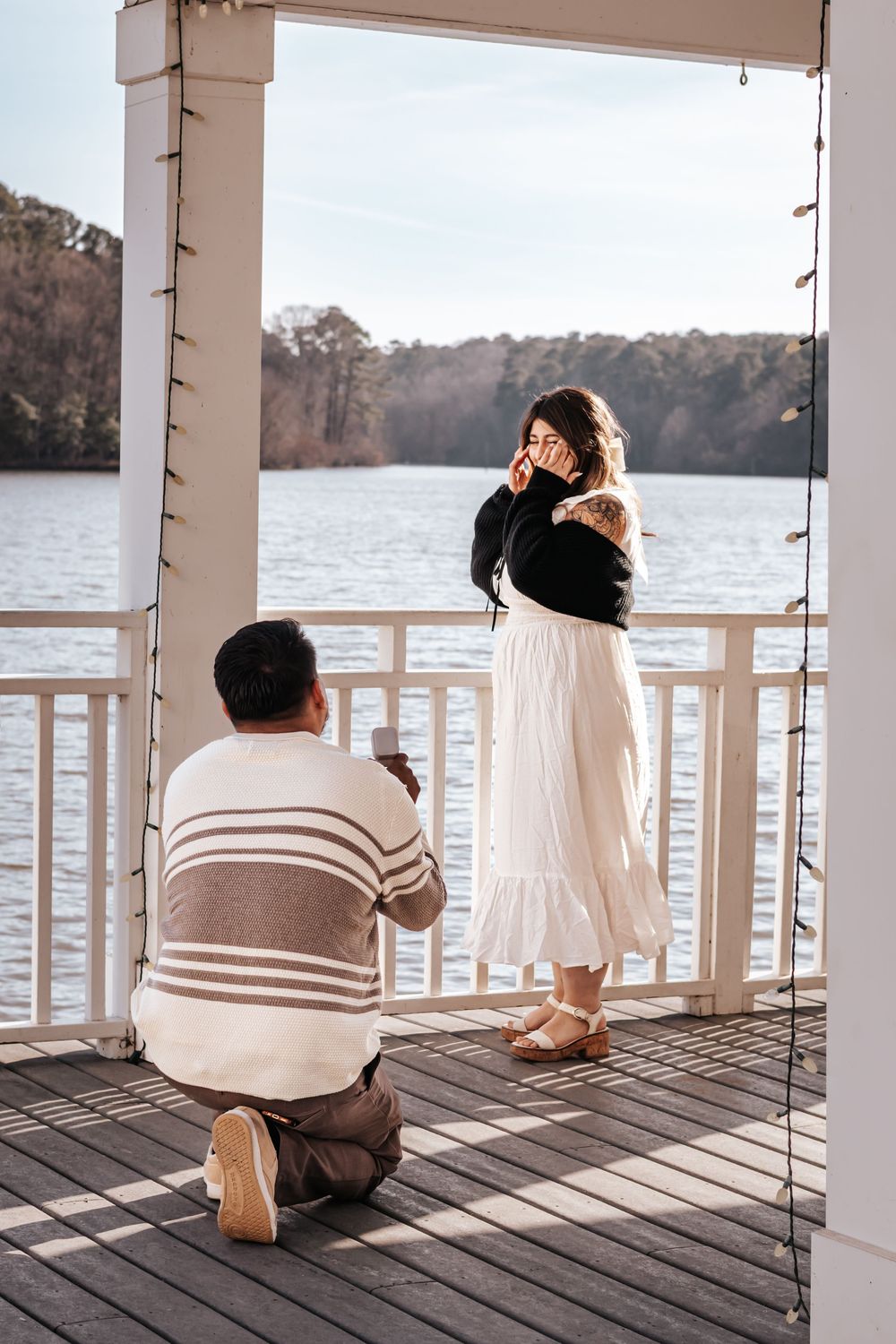 a man proposing to a women in front of a pond