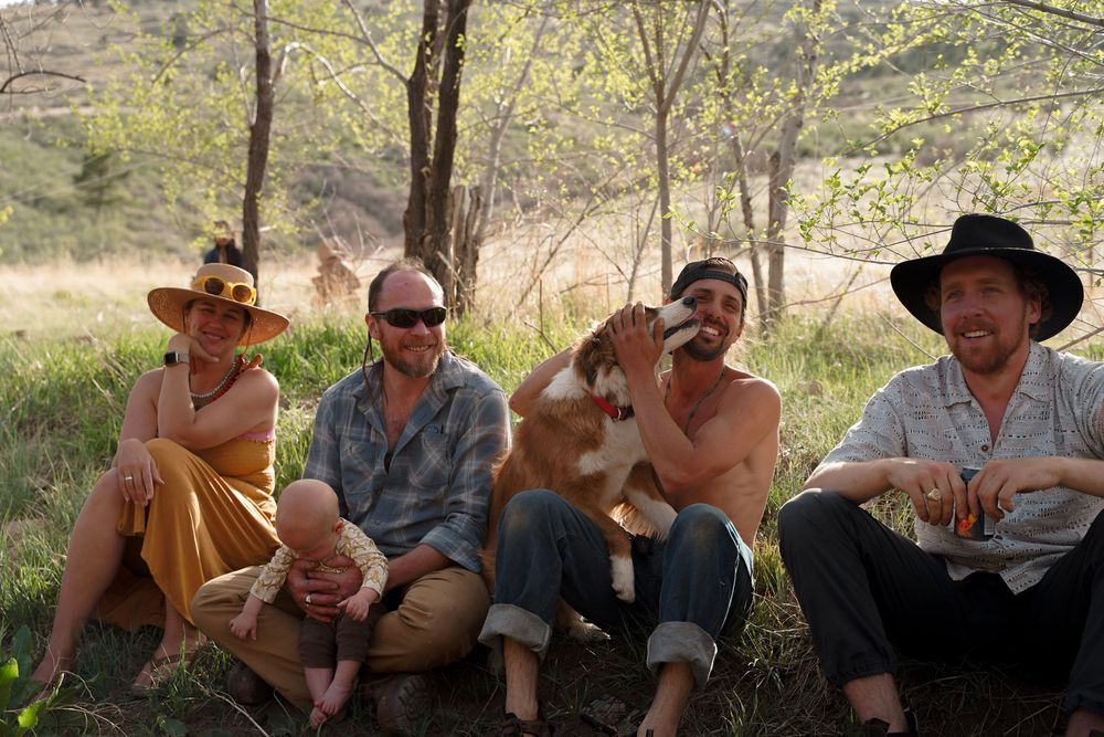 People sitting together outdoors in casual clothing during what appears to be a social gathering or picnic.