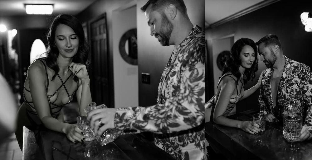 A black and white intimate portrait of a couple interacting in a dimly lit hallway.