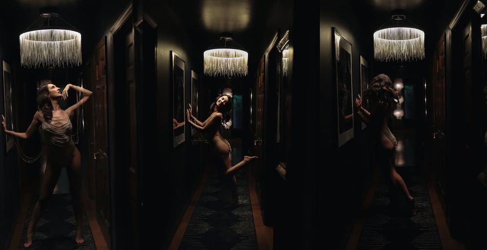 Moody corridor photoshoot with dramatic lighting and mirror reflections creating artistic shadows.