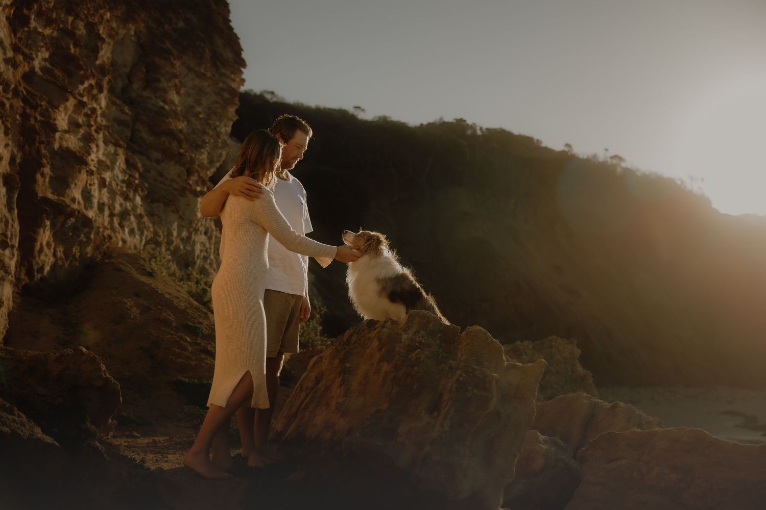 A person in black sits on the ground cuddling a fluffy white Samoyed dog with a happy expression.