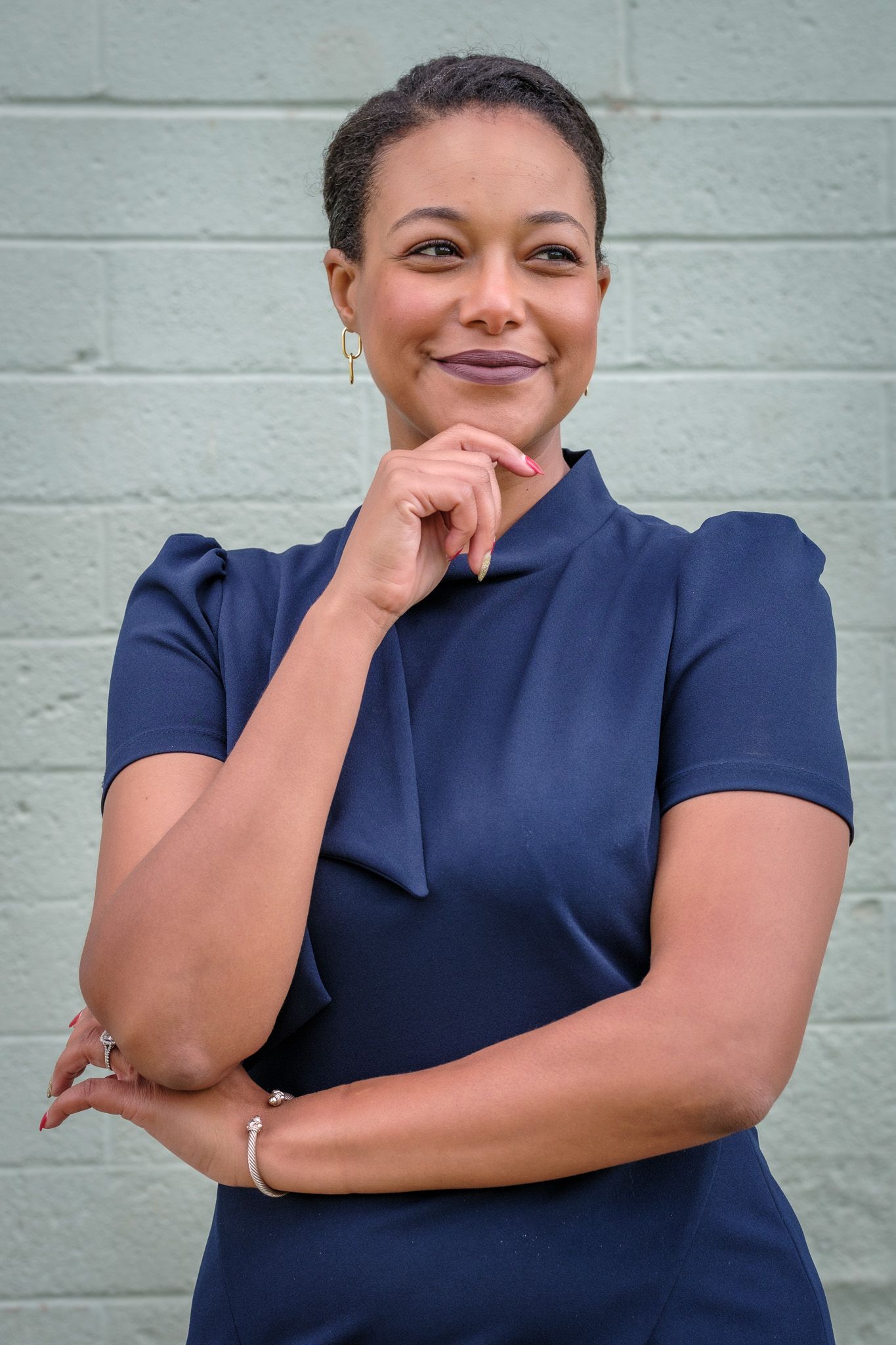 A series of candid portrait shots showing joyful expressions and laughter while wearing a navy blue top against a white wall.