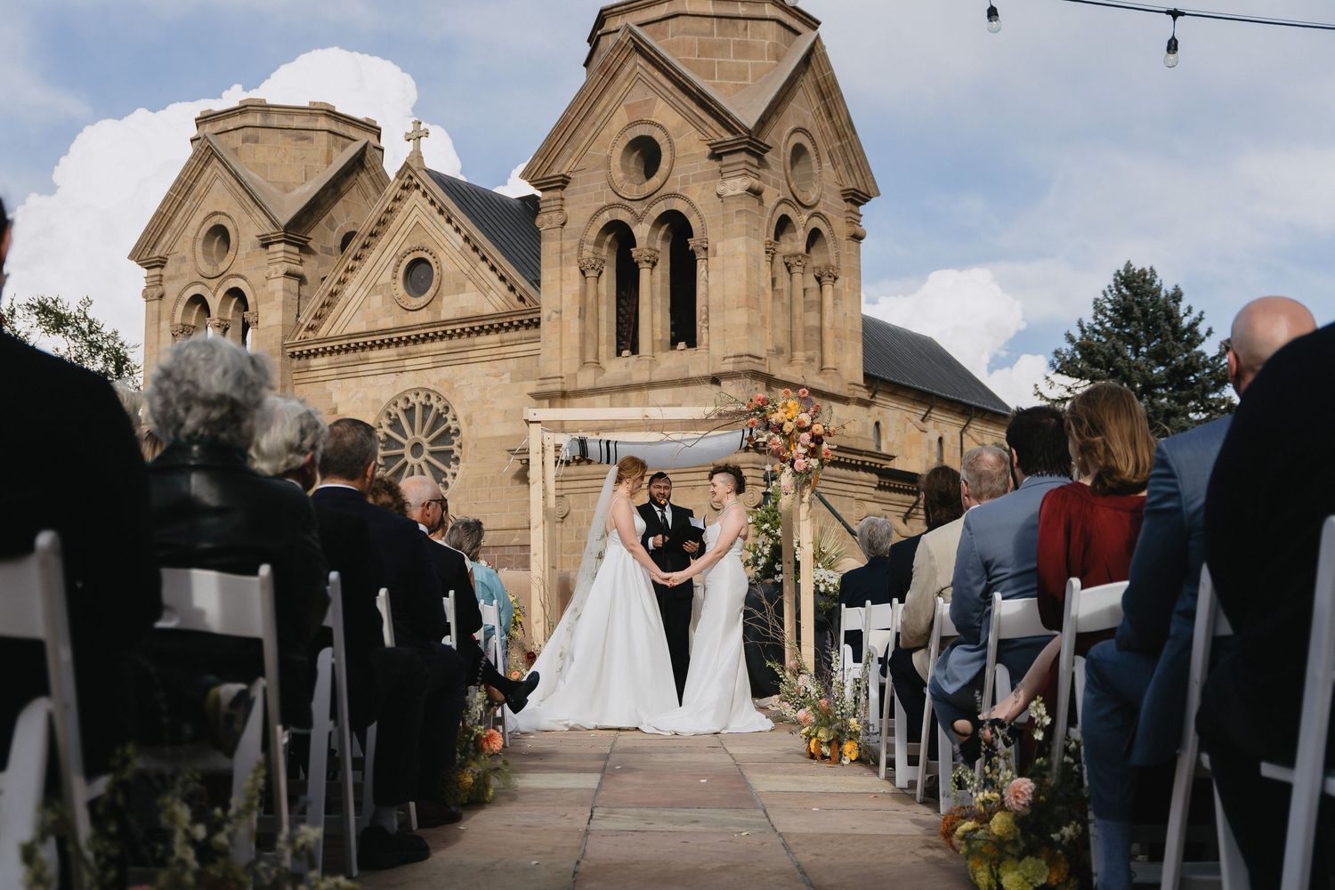 Outdoor wedding ceremony in front of a historic stone cathedral in Santa Fe, New Mexico.cinematic wedding photographer new mexico