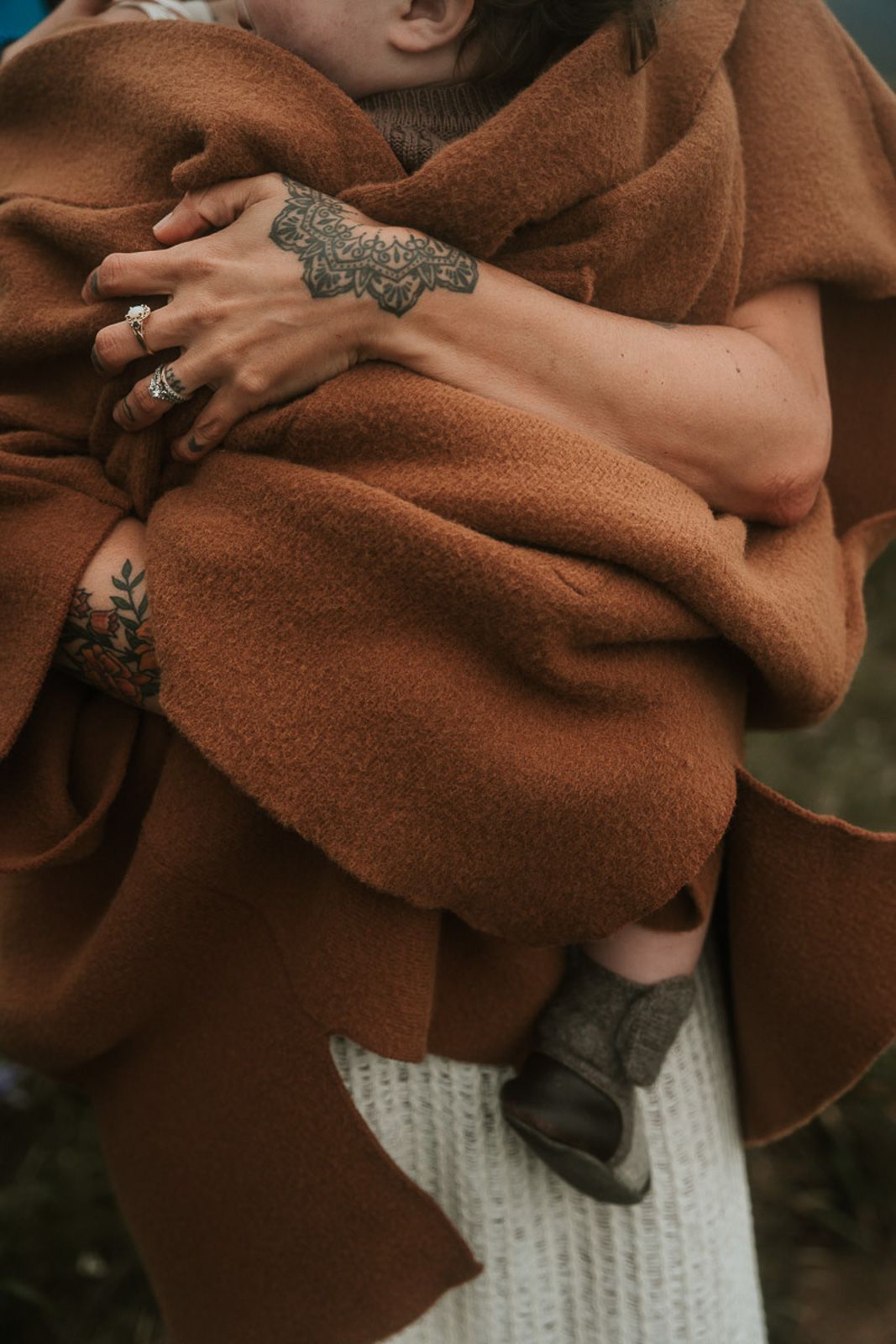 Close-up of hands wearing ornate rings against brown sweater sleeve and white knit cuff detail during a fall mini
