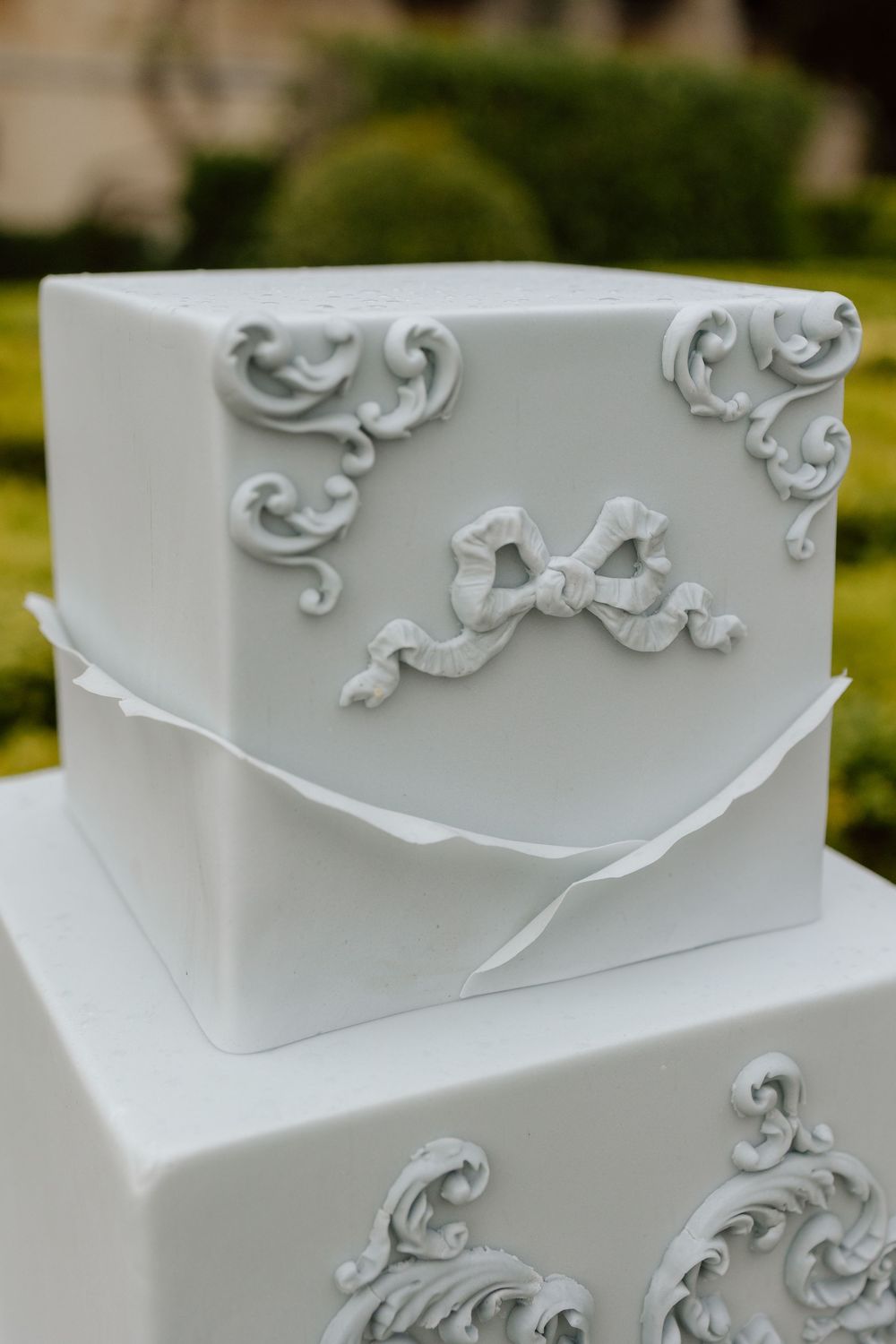 Close-up of an elegant white wedding cake with delicate scroll work and ornate filigree patterns in classic baroque style.
