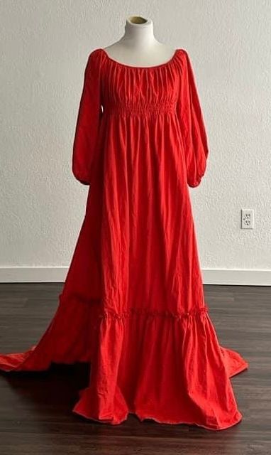 A vintage-inspired lace wedding dress with empire waist and flowy train displayed on a cream mannequin form.