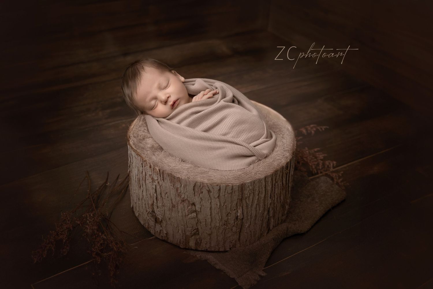 Artistically styled newborn photography session showing baby sleeping in soft beige tones and rustic textures.