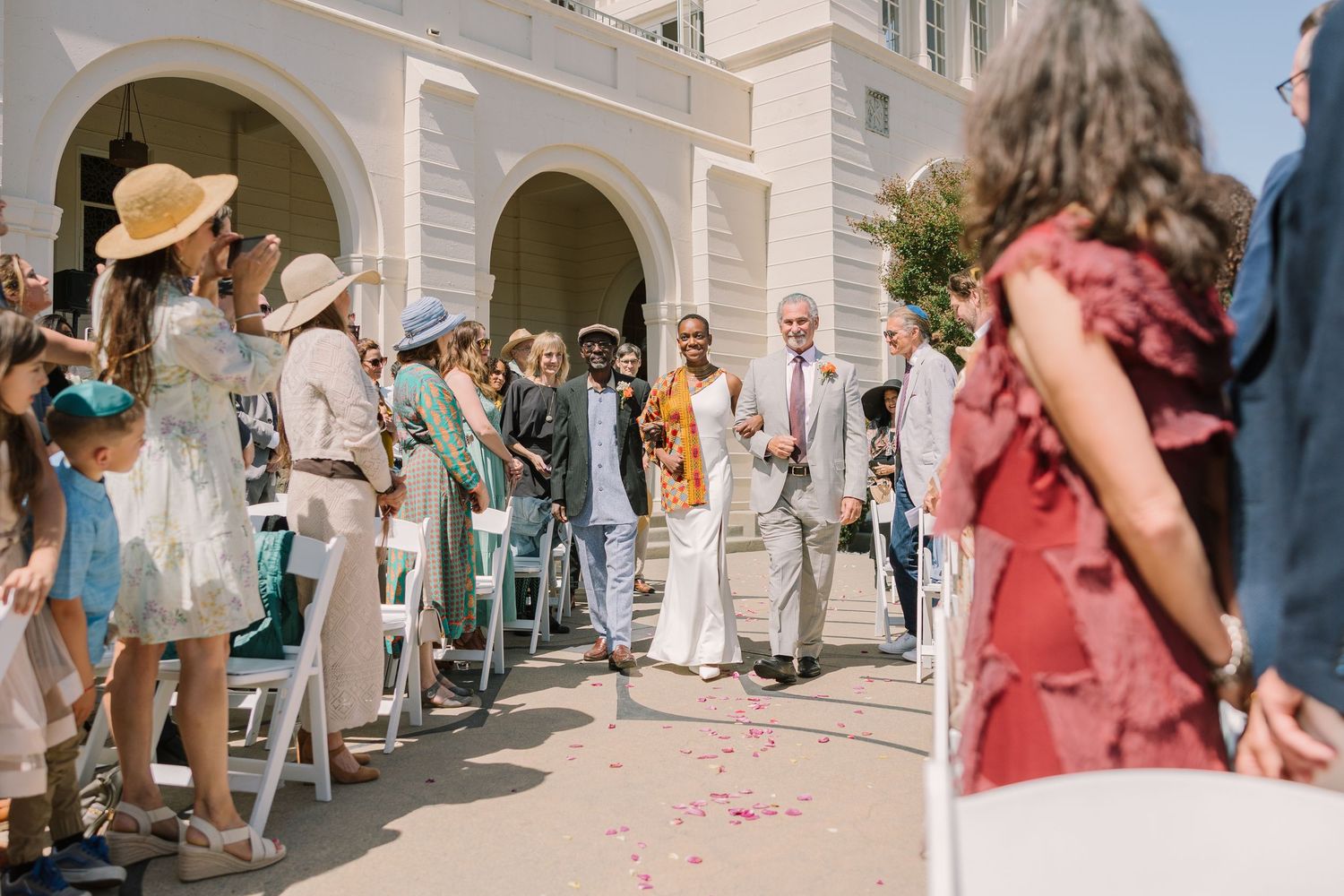 bride and fathers c walks through a petal toss entrance under the archways at Geneva Terrace, Redlands University.