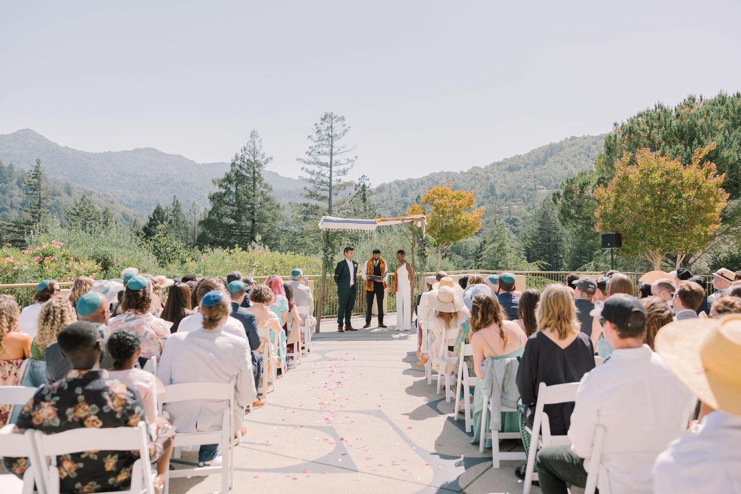 Wide view of seated wedding guests during the outdoor ceremony at Geneva Terrace, surrounded by California hills and trees.