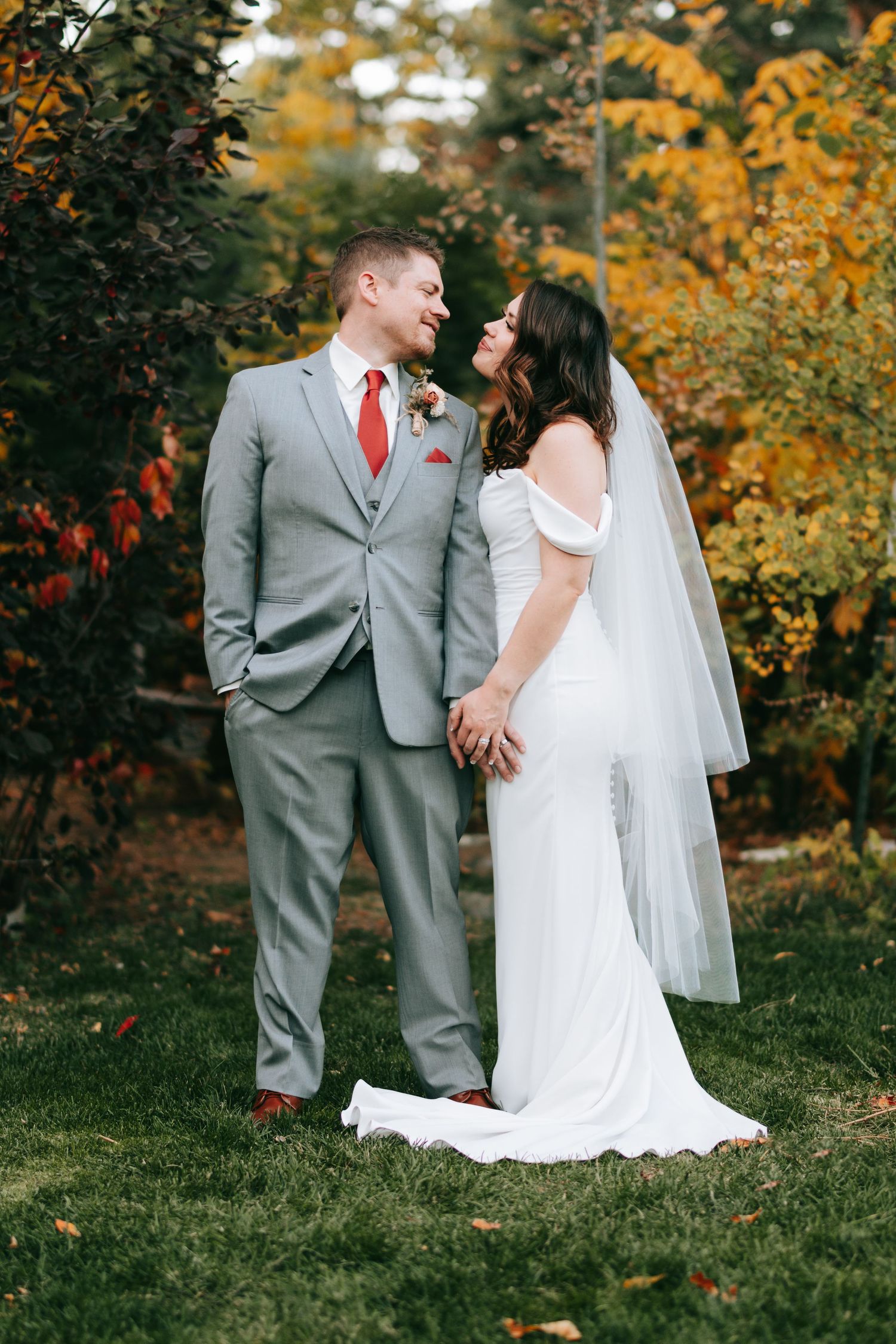 A wedding couple sharing a loving moment against vibrant fall foliage.