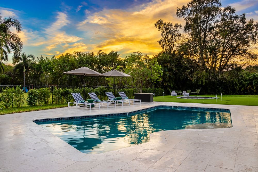 Infinity pool reflecting golden sunset sky with tropical landscaping in the background.