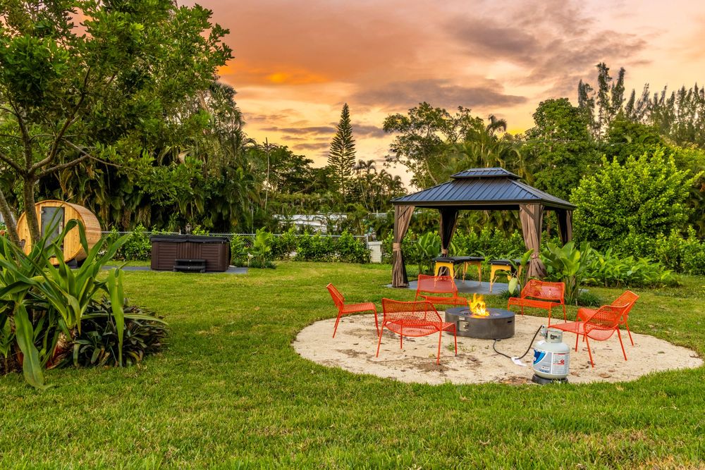 Outdoor seating area with orange chairs arranged around a circular patio space surrounded by greenery.