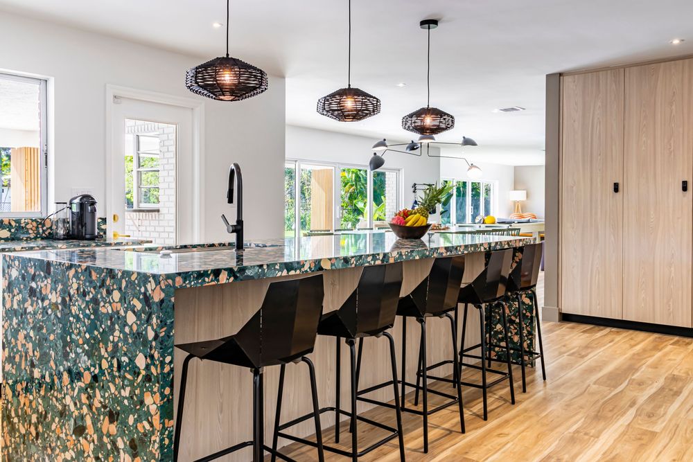 Contemporary bar area with black high stools and pendant lighting along a sleek wooden counter.