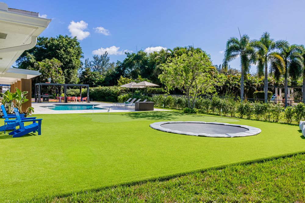 Modern backyard with lush green lawn, palm trees, and a circular paved area perfect for outdoor entertaining.