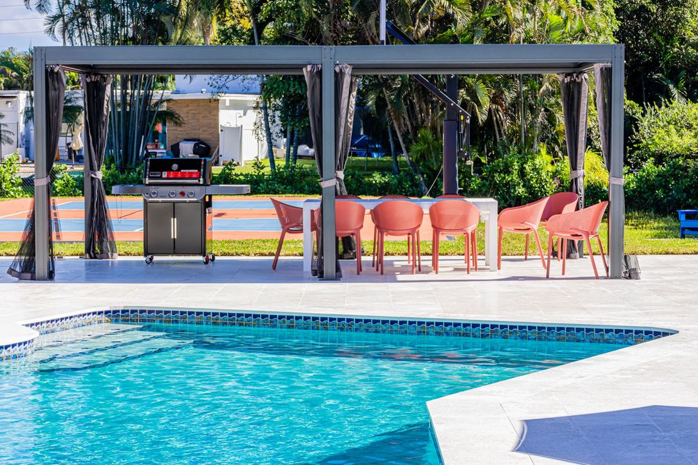 Resort-style swimming pool with covered cabana seating and red lounge chairs on the deck.