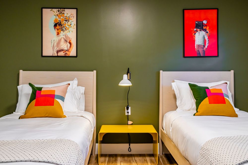Stylish bedroom interior with olive green walls, white bedding, and contemporary wall art.