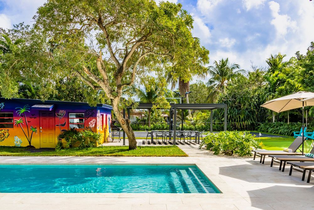 Expansive backyard paradise featuring a swimming pool, palm trees, and manicured lawn under blue skies.