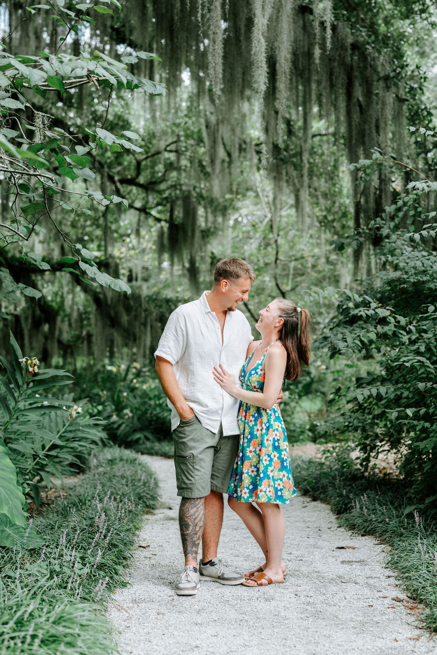 A couple sharing joyful moments on a nature trail surrounded by hanging moss and greenery.