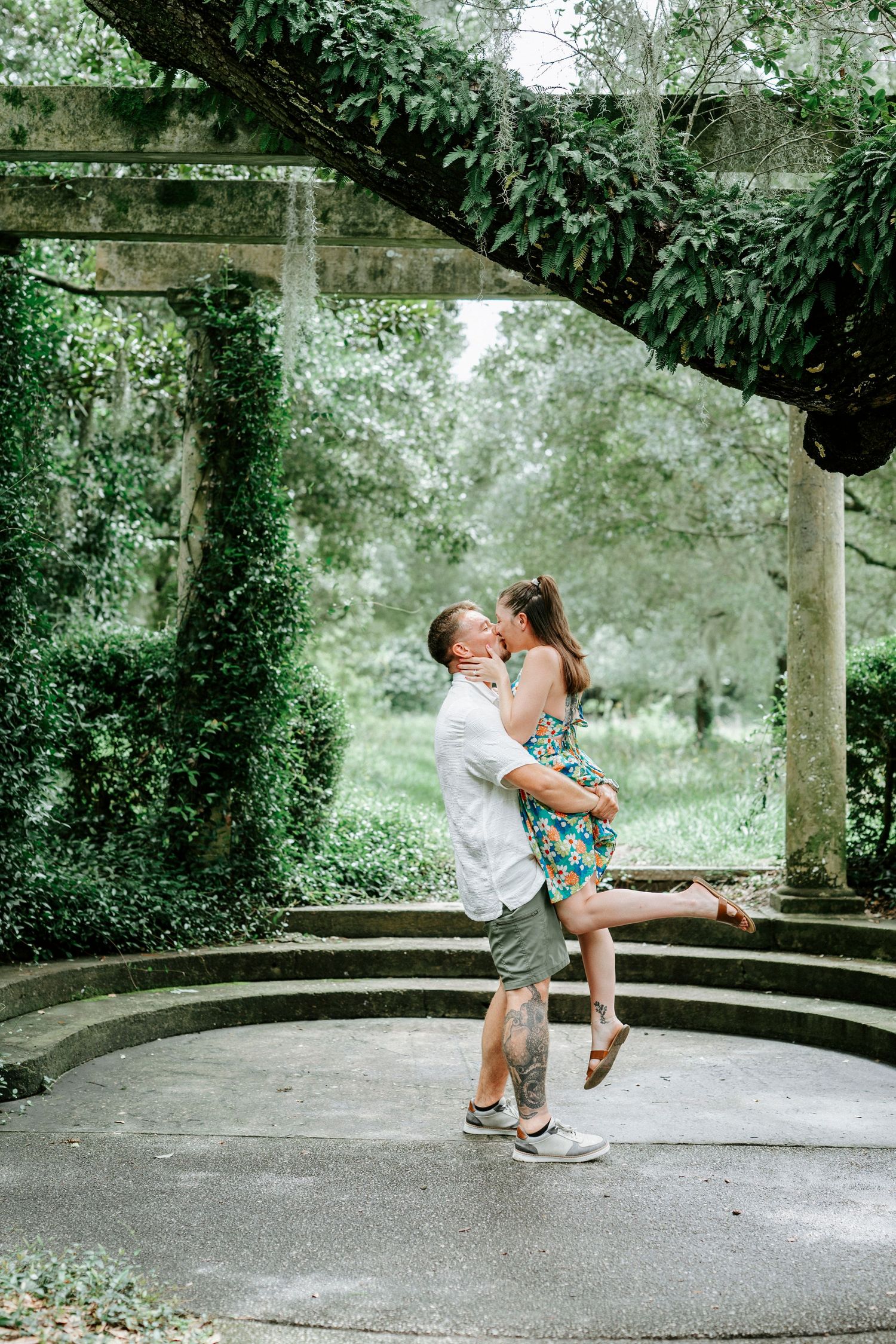 A romantic dance sequence on a curved concrete path surrounded by lush greenery.