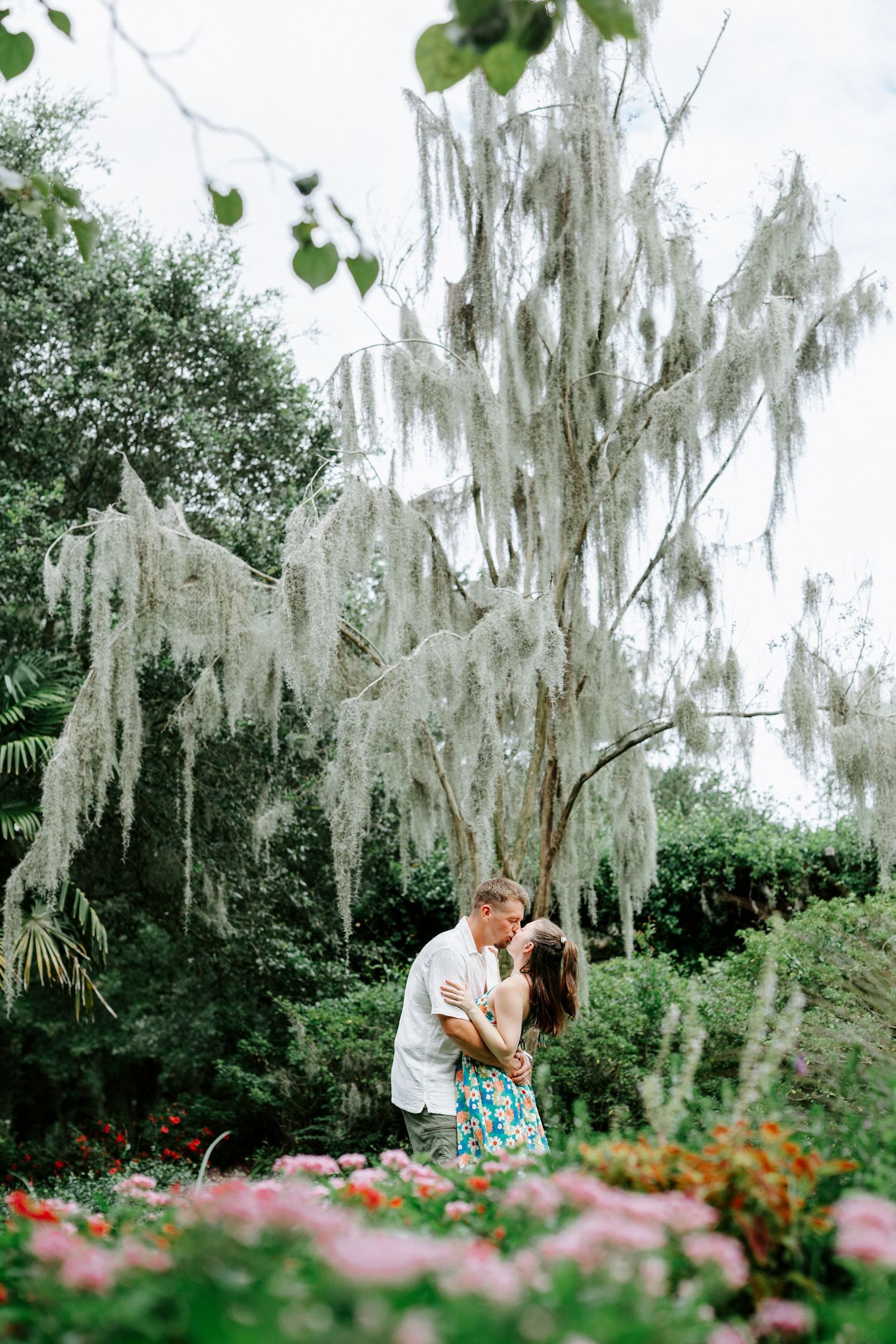 A romantic photo sequence under white flowering trees with pink flowers in the foreground.