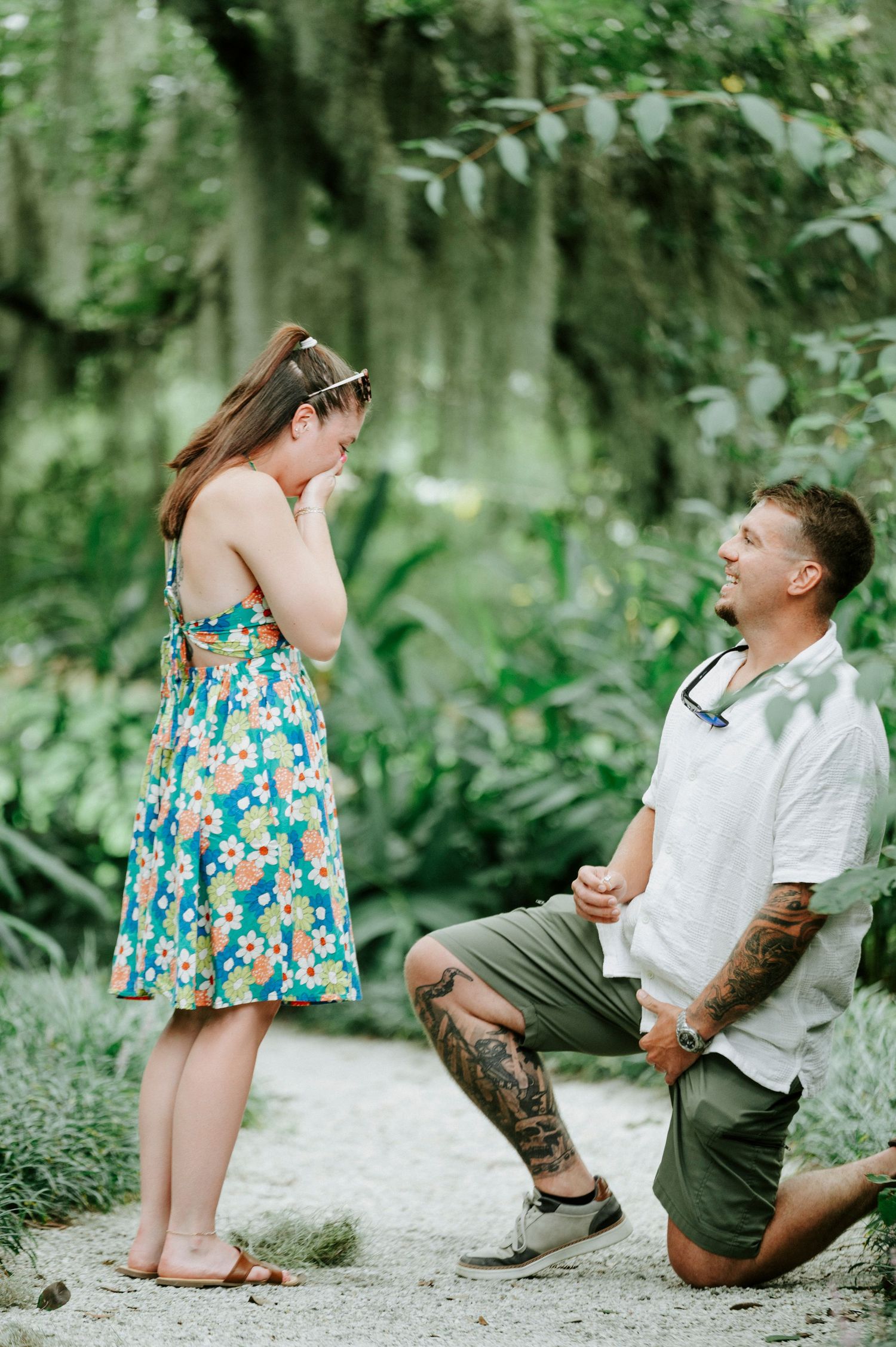 A surprise proposal moment captured on a garden path with Spanish moss overhead.