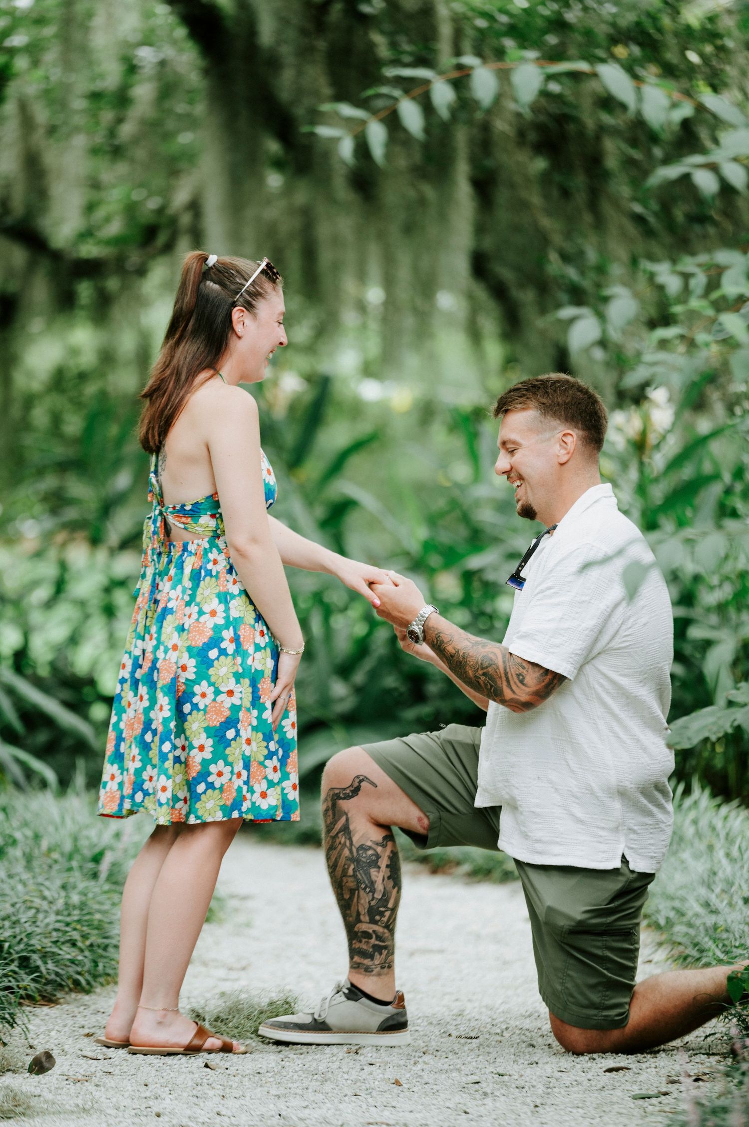 A marriage proposal unfolds on a garden path as one person kneels.
