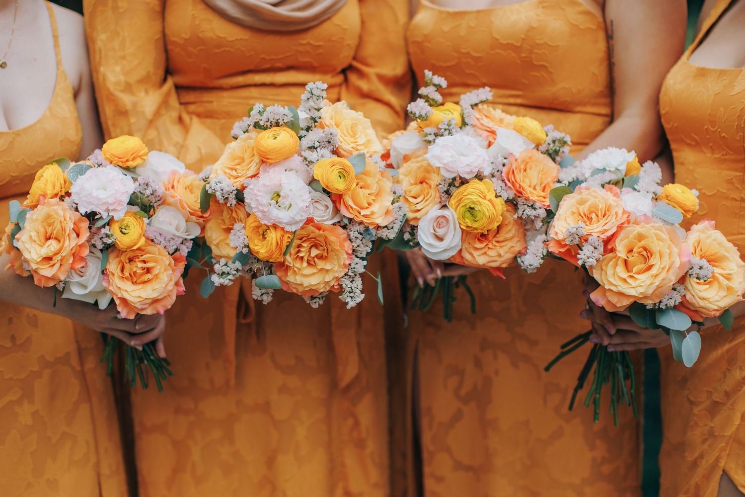 Close-up of peach and orange floral wedding bouquet arrangements.