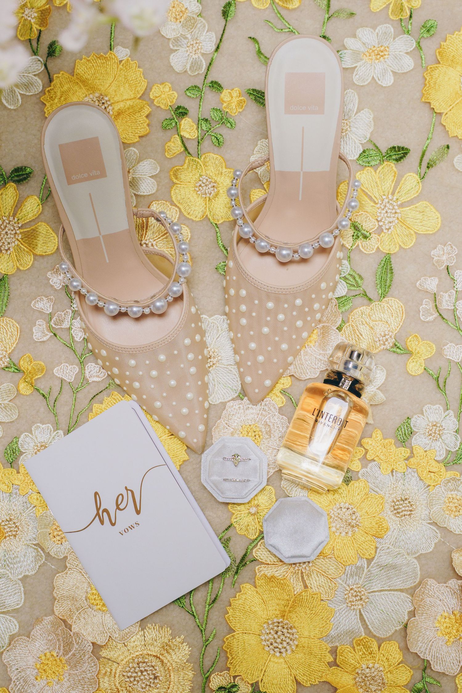 Wedding accessories including shoes and jewelry arranged on yellow floral background.