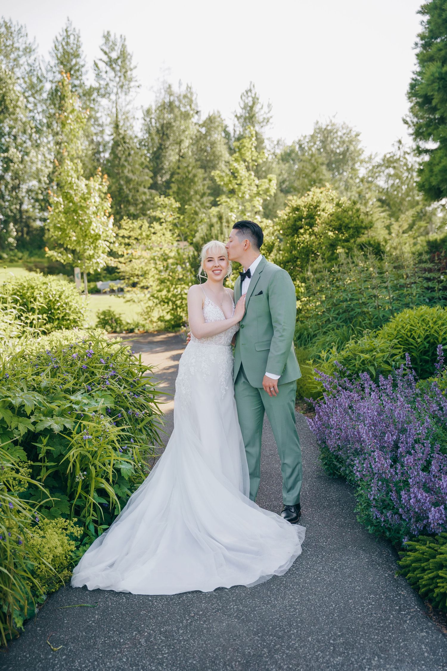 Garden wedding portraits with purple flowers and greenery creating a romantic backdrop.
