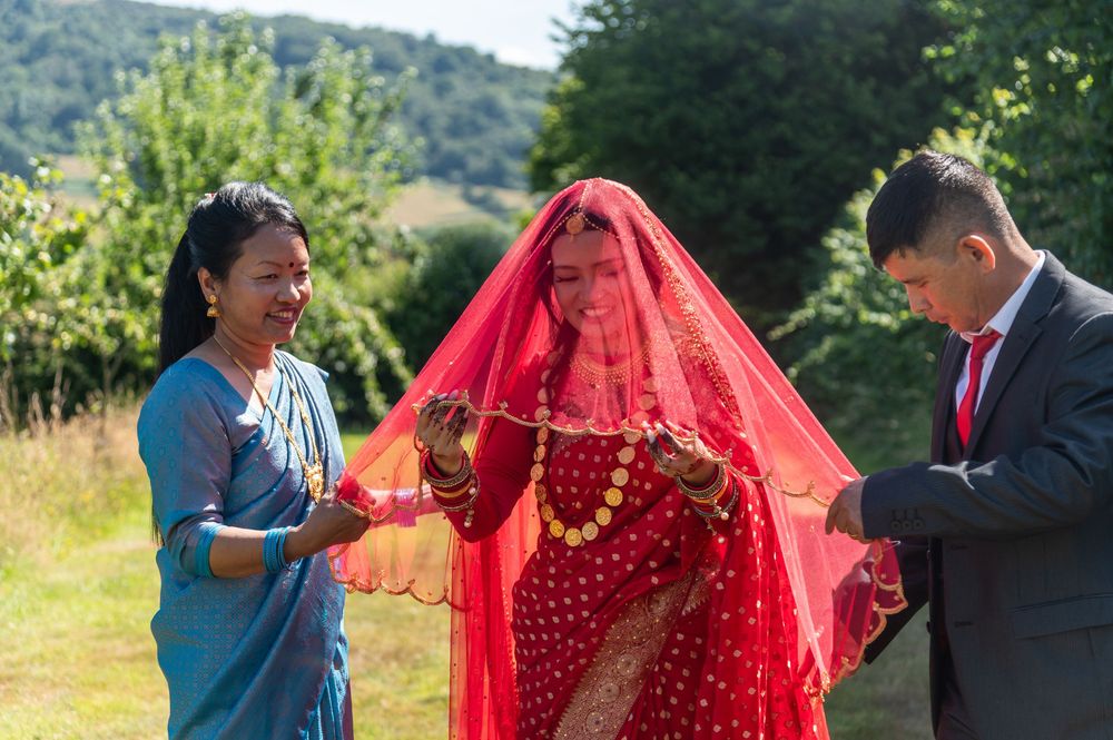 Outdoor wedding celebration with guests in vibrant traditional clothing against a mountain backdrop.