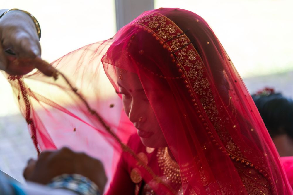 Close-up of red and gold embroidered wedding attire with traditional Indian details.