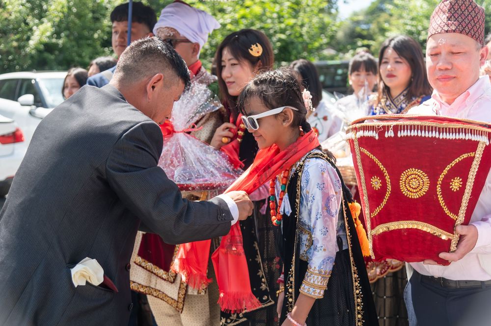 Outdoor wedding celebration with guests in traditional Indian attire and white headwear.
