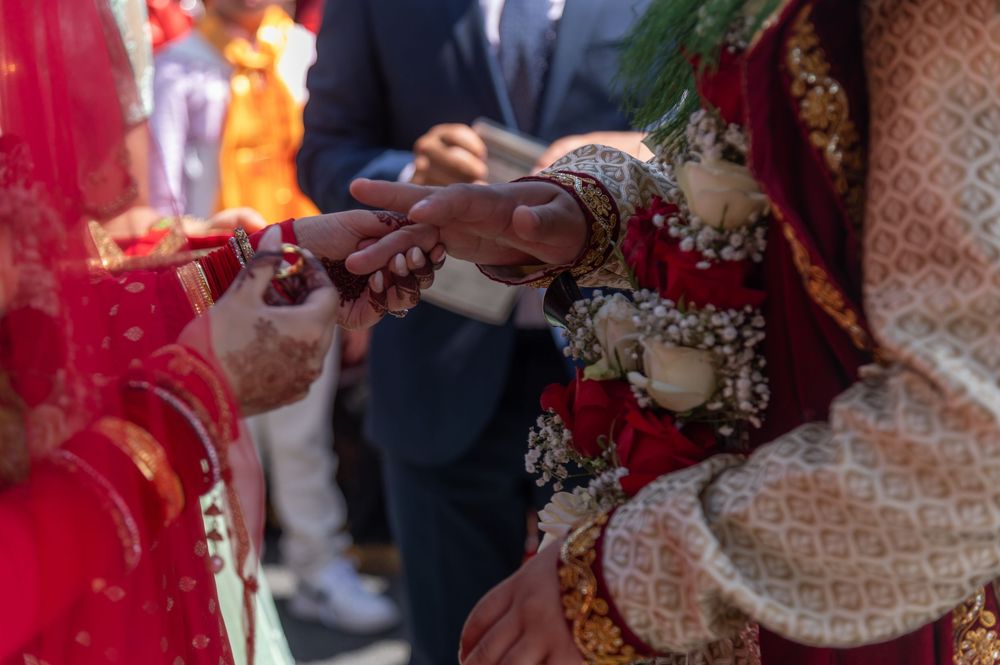 Close-up details of traditional Indian wedding ceremony with red and gold decorative elements and clothing.