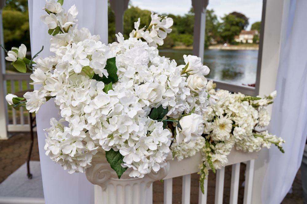 Beautiful white hydrangea flowers decorate a white railing overlooking a waterfront venue.