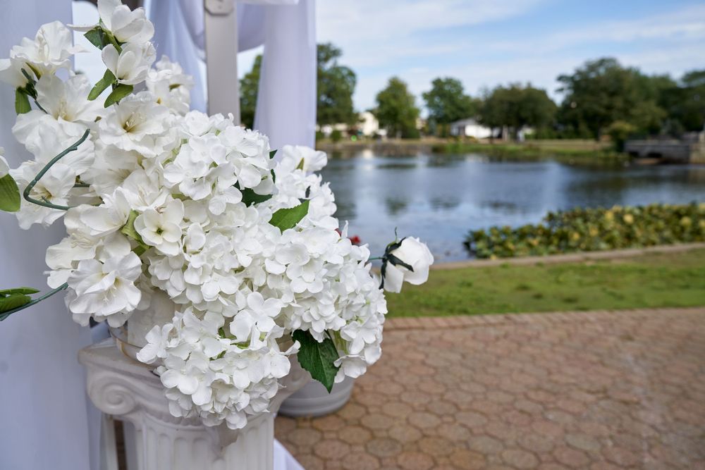 White hydrangea floral arrangement on a post with a serene lake view in the background.