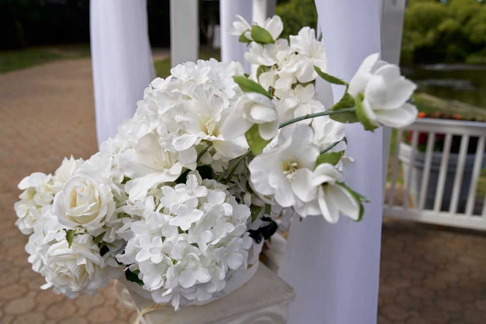 Elegant white floral arrangement with hydrangeas and roses attached to a white column.