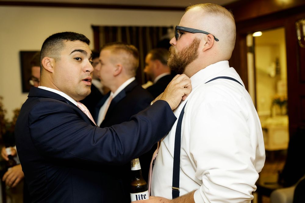 Two formally dressed people adjusting clothing before an event.